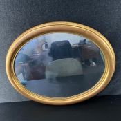 A contemporary wall mirror having a faux aged oval plate in a simple gilt frame. 59x49cm