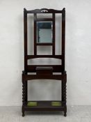 An Edwardian oak hall stand having a shaped openwork top rail over a rectangular bevelled mirror