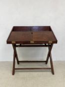 A campaign style two part leather desk with fall front enclosing fitted interior and pull-out