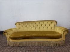 A three seater sofa with deep buttoned upholstery and roll arms with long single cushion. Originally