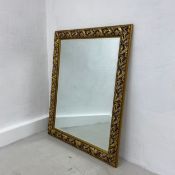 A large contemporary wall mirror having a rectangular bevelled plate in a gilt scrolling foliate
