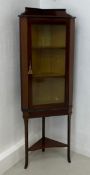 An Edwardian mahogany and satinwood strung corner cabinet on stand with a glazed door enclosing a