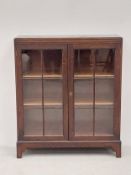A mid century oak dwarf bookcase with glazed doors enclosing bookshelves on shaped bracket feet. H.