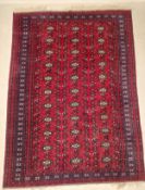 A large possibly 19th century Afghan style Bukhara carpet having three rows of eleven guls over a