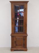 A vintage oak display cabinet having a dentil moulded cornice over a single glazed door enclosing an