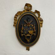 A possibly 19th century carved and painted armorial giltwood plaque having a central heraldic