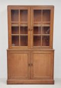 An early 20th century two section light oak library bookcase the upper glazed section above panel