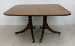 A Georgian mahogany dining table with three extra leaves on later but matching swept tripod pedestal