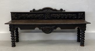 A late 19th century carved oak hall bench or window seat with carved back above plank seat on