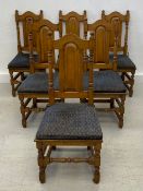 A set of six Jacobean style oak dining chairs with arched backs above panel seats fitted with