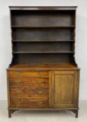 An early 20th century oak dresser in two parts having shaped open bookshelf over a chest of four