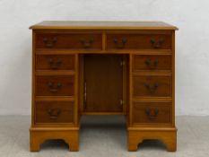 A contemporary Georgian style yew-wood kneehole desk having a gilt and tooled green leather top over