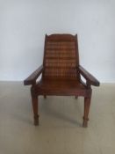 A vintage teak planters chair with caned seat and hinged leg rests. W.61cm