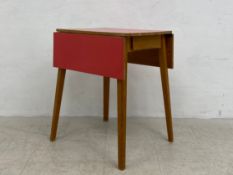 A mid-century kitchen table having a square composite laminated top with two drop-leaves over a