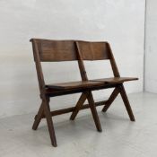 An early 20th century oak folding two seat chapel bench having a curved top rail over two saddle