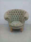 A contemporary Andrew Martin accent armchair having a curved and scrolled deep-buttoned back and