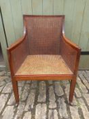 A late 19th century mahogany bergere armchair having a square rattan back and shaped arms raised
