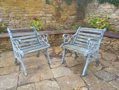 A pair of teak slatted garden armchairs with scrolling wrought iron ends. H.75 W.62cm (One with