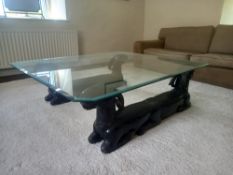 A vintage coffee table having a square bevelled glass top with canted corners raised on a pair of