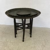 An Eastern folding table with embossed copper tray top along with two similar Eastern trays. 72cm