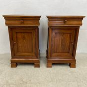A pair of Victorian style teak bedside cabinets with frieze drawer above panel door on shaped