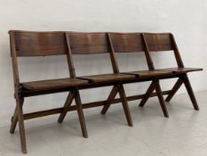 An early 20th century oak folding four seat chapel bench having a curved top rail over four shaped