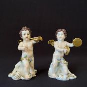 A pair of Continental porcelain cherubs with musical instruments, marked to bases. H.12.5cm