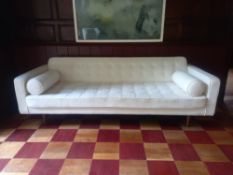A contemporary 1960's style sofa with buttoned upholstered back and seats on circular teak supports.