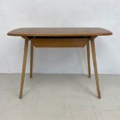 A mid-century Ercol beech and elm writing table fitted with frieze drawer and with maker's label