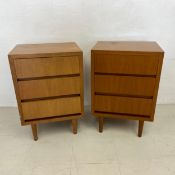 A pair of mid-century teak bedside tables, each with three drawers raised on circular section