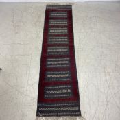 A flatweave Kelim runner with a geometric design on a slate ground. 305x76cm