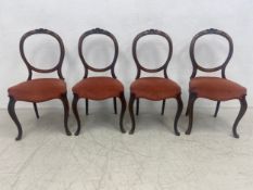 A set of four Victorian carved mahogany dining chairs with serpentine fronted stuffover seats on