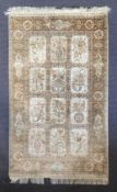 A Persian silk rug with flowerhead bird, urn and cornucopia decoration across the biscuit field