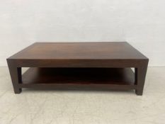 A contemporary hardwood coffee table with rectangular top raise on square tapering supports united