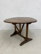 An 18th or 19th century French elm tilt-top wine tasting table having a circular undulating top with