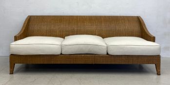 A modern American woven rattan three seater conservatory sofa with loose calico upholstered cushions