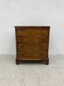 An early 20th century Georgian style bow fronted bachelors chest of four long graduating drawers