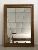 A contemporary wall mirror with rectangular bevelled plate in a scrolling gilt frame. 110x80cm