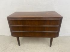 A small mid-century Danish style teak chest with three long drawers raised on circular tapering