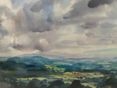 A 20th century watercolour depicting an expansive landscape under moody skies in a glazed frame.