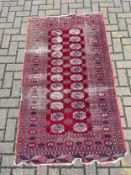 A Bokhara rug with repeating gul medallions on a burgundy ground within multiple geometric