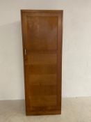 A mid-century oak wardrobe with single panelled door enclosing hanging section with maker's