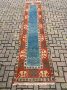 A hand knotted woollen runner with central pale blue panel in stylised multiple borders. 336x82cm