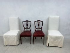 A pair of 19th century mahogany shield back dining chairs with reupholstered red leather stuffover