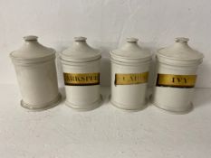 Four 19th century porcelain lidded apothecary's jars, three with hand decorated labels. H.22cm