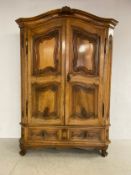 A 19th century chestnut armoire having a shaped and moulded pediment with shell cresting over a pair