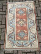 A Turkish rug with repeating flowerhead medallions on a terracotta field within geometric borders.