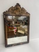 An early Georgian carved giltwood wall mirror having a Rococo style cresting over the original plate