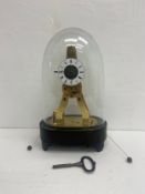 A small brass skeleton clock with engraved plates and cord operated alarm with glass dome on