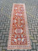 A Ziegler style runner with stylised foliate decoration on a terracotta ground. 264x79cm (Joined